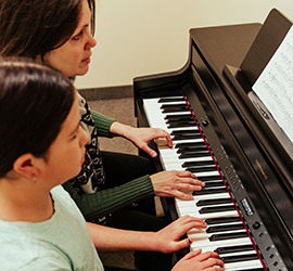 Teacher and student playing the piano