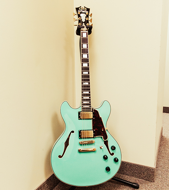 An electric guitar standing against a wall