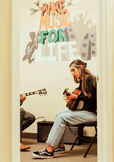 Girl playing guitar with music teacher